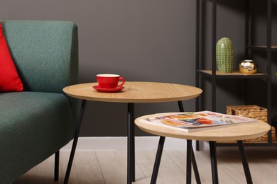 Photo of Nesting tables with coffee and magazine near sofa indoors. Interior design