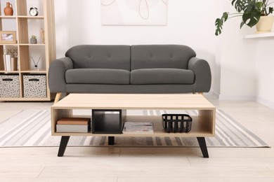 Photo of Stylish coffee table in front of sofa at home. Interior design