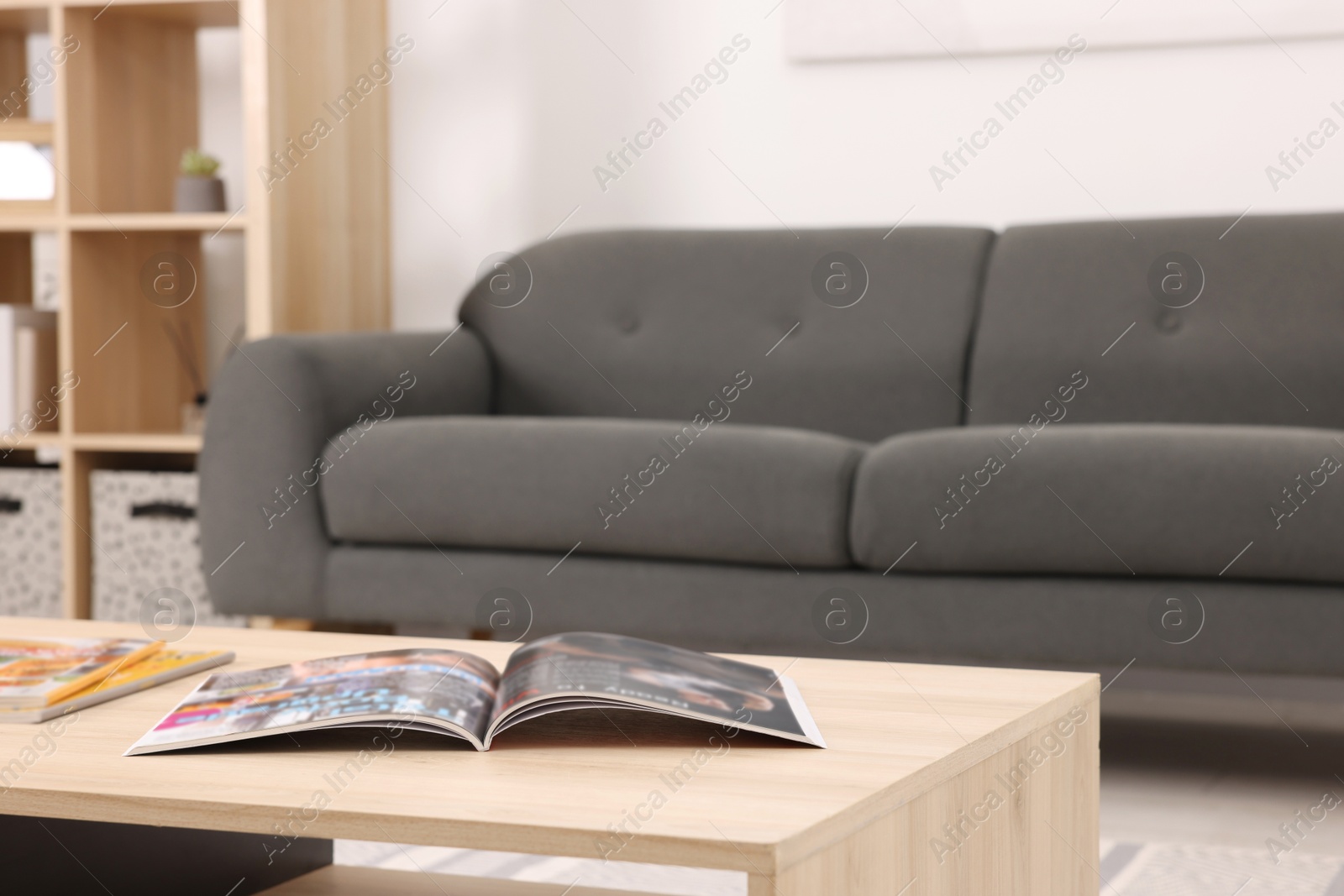 Photo of Wooden coffee table with magazines near sofa at home