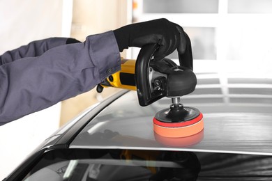 Photo of Man polishing car with orbital polisher indoors, closeup