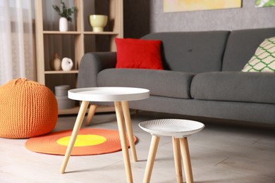 Photo of Stylish nesting tables near sofa at home