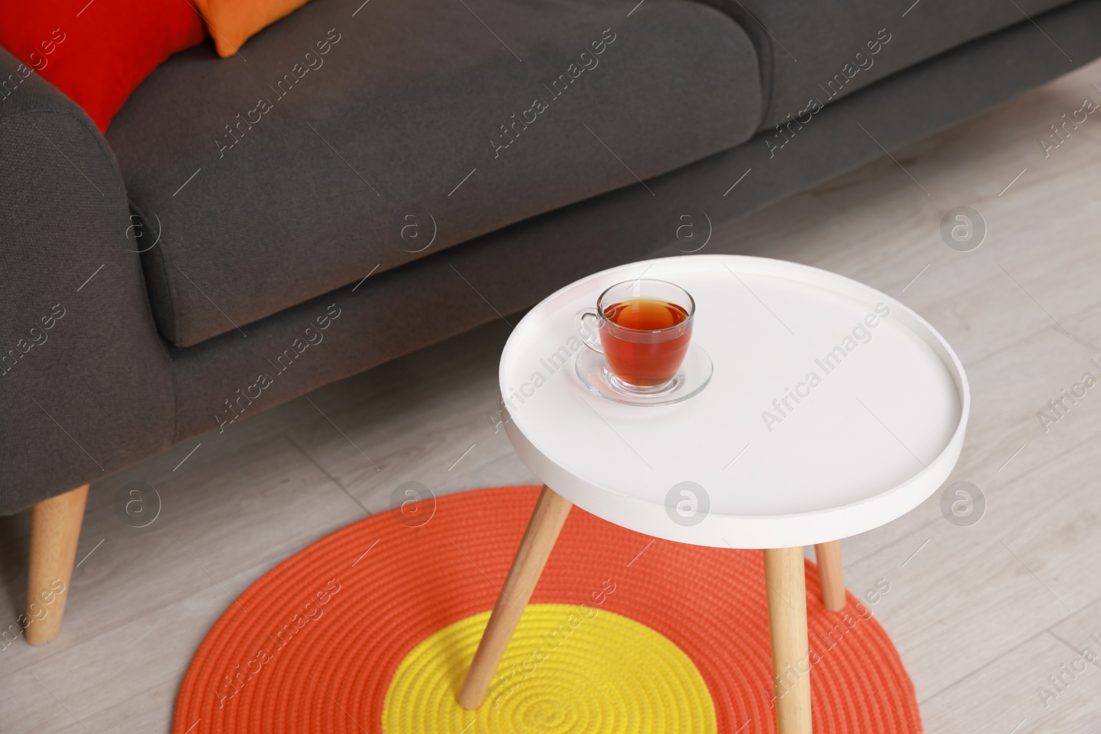 Photo of Coffee table with cup of tea near sofa at home