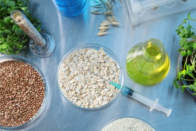 Photo of GMO concept. Different raw grains in petri dishes, microgreens, syringe and other equipment on table in laboratory, flat lay