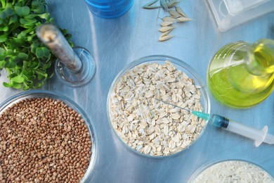 Photo of GMO concept. Different raw grains in petri dishes, microgreens, syringe and other equipment on table in laboratory, flat lay