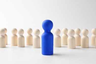 Photo of Blue figure standing out among others on white background. Competition concept