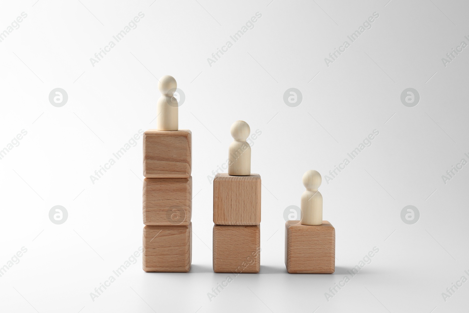 Photo of Human figures on stacked wooden blocks against white background. Competition concept