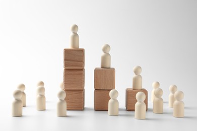 Photo of Human figures on stacked wooden blocks against white background. Competition concept