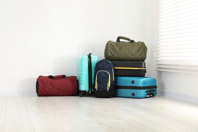 Photo of Colorful suitcases, backpack and bag on floor near white wall