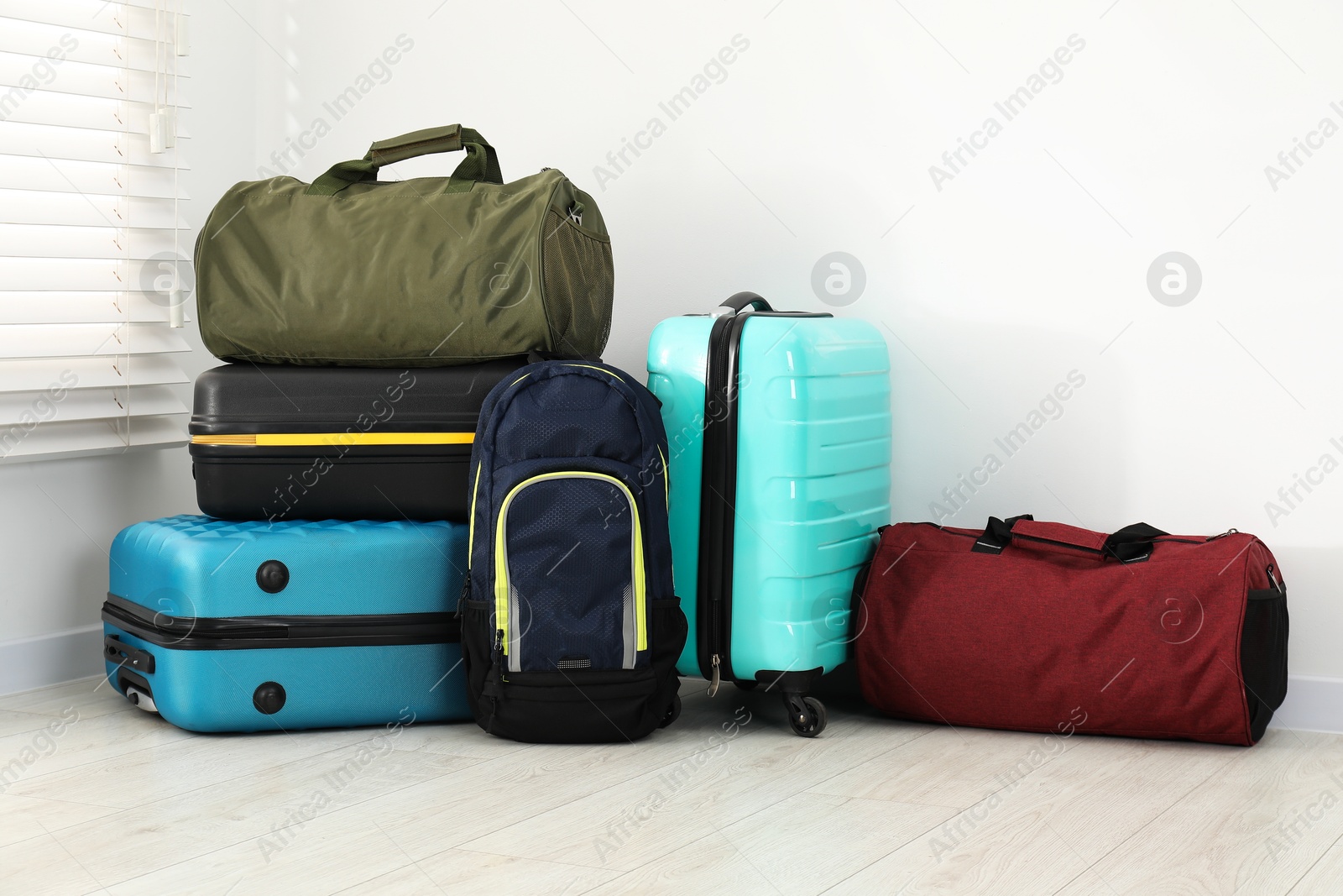 Photo of Colorful suitcases, backpack and bag on floor near white wall