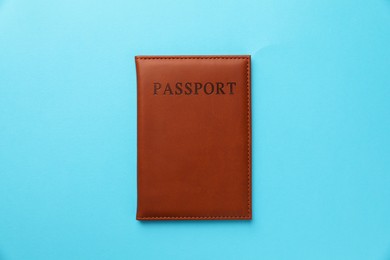 Photo of Passport in brown cover on light blue background, top view