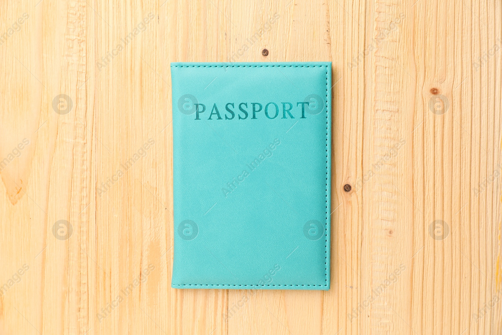 Photo of Passport in light blue cover on wooden table, top view