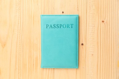 Photo of Passport in light blue cover on wooden table, top view