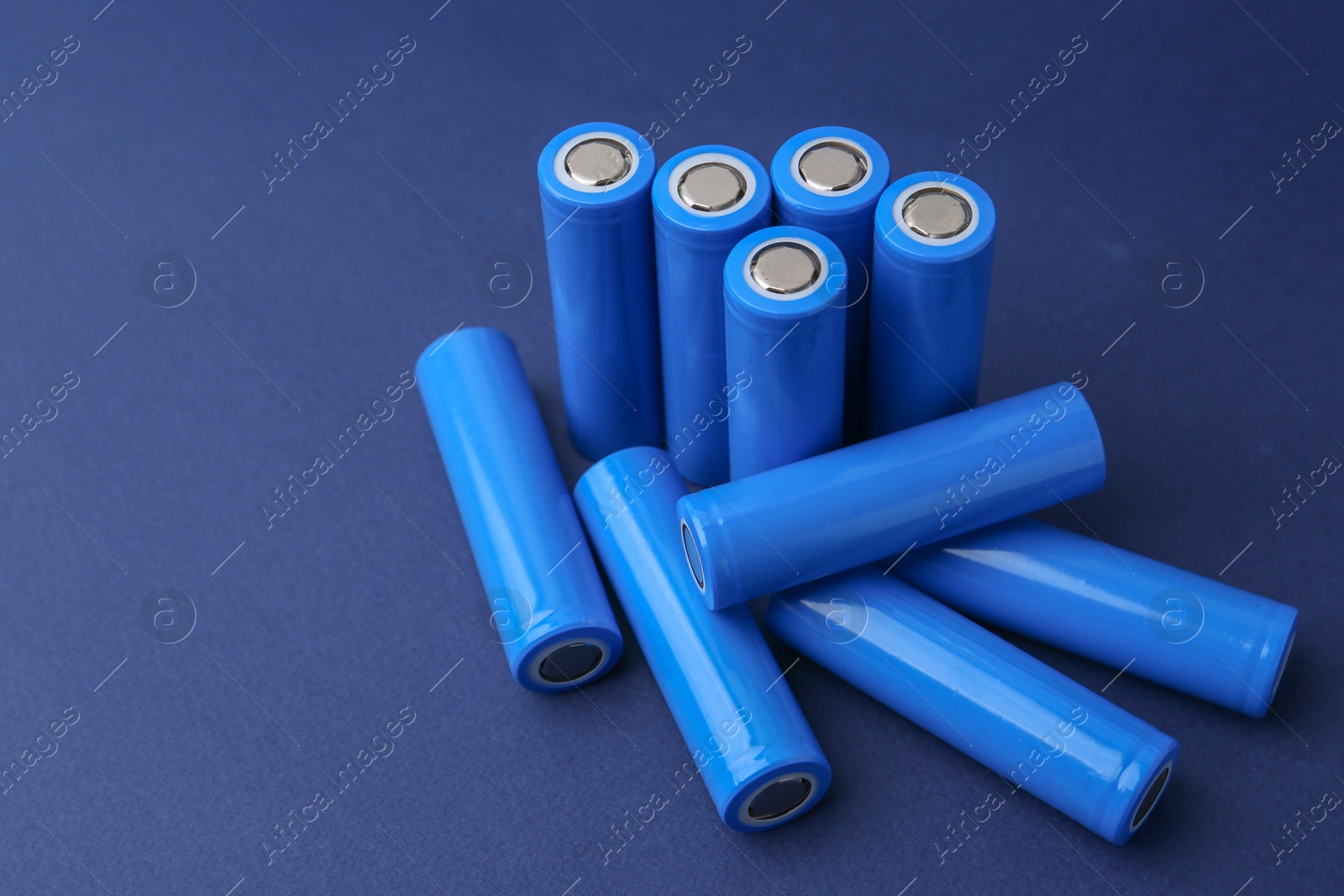 Photo of Many AA cell batteries on blue background, closeup. Space for text