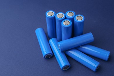 Photo of Many AA cell batteries on blue background, closeup. Space for text