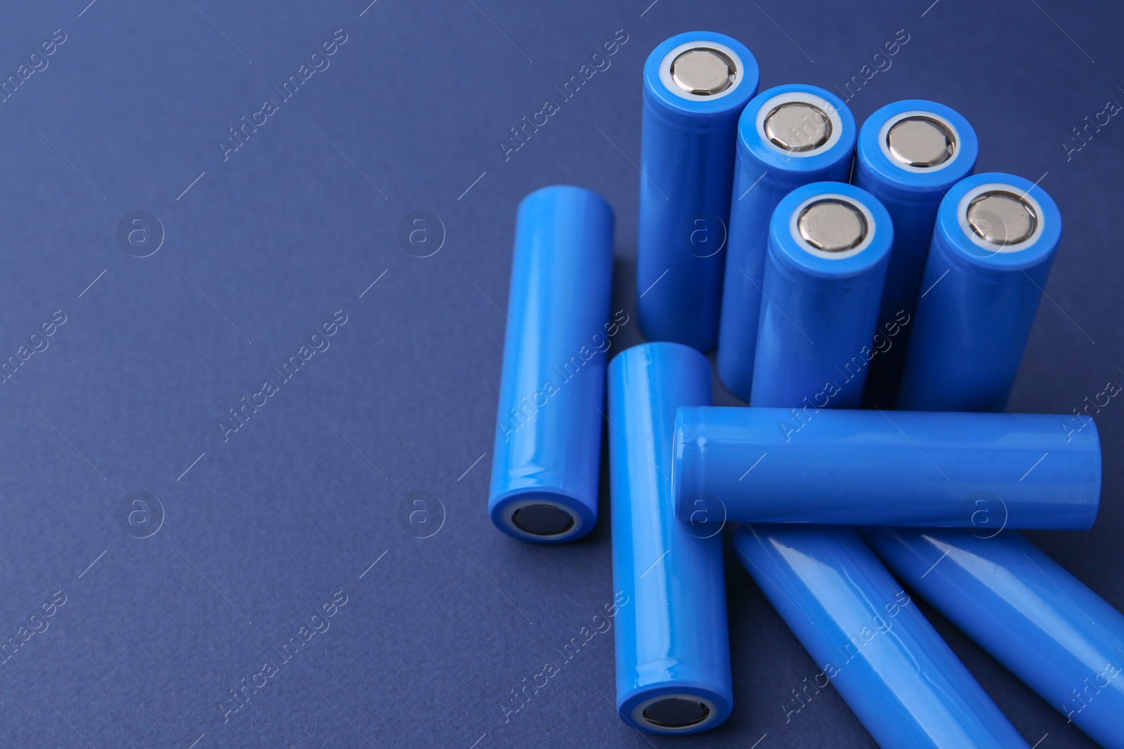 Photo of Many AA cell batteries on blue background, closeup. Space for text