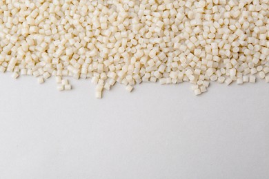 Photo of Pile of plastic granules on white background, top view. Space for text