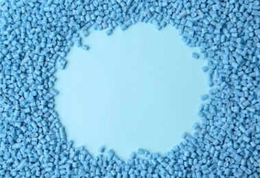 Photo of Frame of plastic granules on light blue background, top view. Space for text