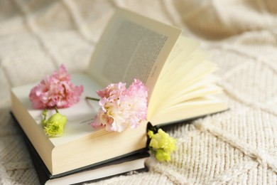 Open book with beautiful flowers on blanket, closeup