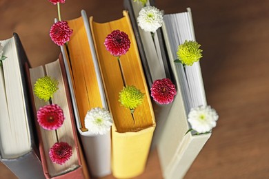 Different books with beautiful flowers on blurred background, closeup