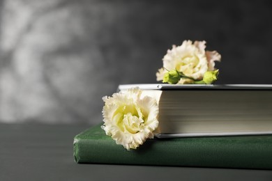 Photo of Books and beautiful flowers on grey wooden table, closeup. Space for text