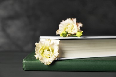 Photo of Books and beautiful flowers on grey wooden table, closeup