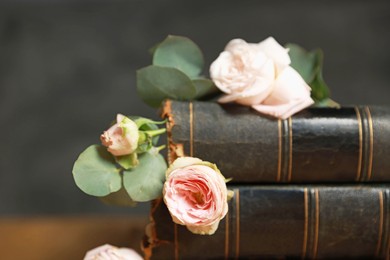 Stack of books with beautiful flowers and eucalyptus branches on blurred background, closeup