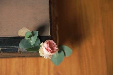 Photo of Stack of books with beautiful flower and eucalyptus branches on wooden table, top view. Space for text