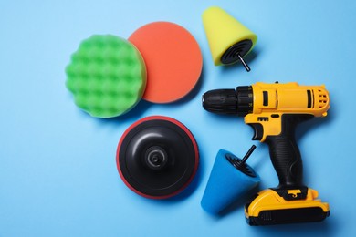 Photo of Electric screwdriver with different polish pads on light blue background, flat lay