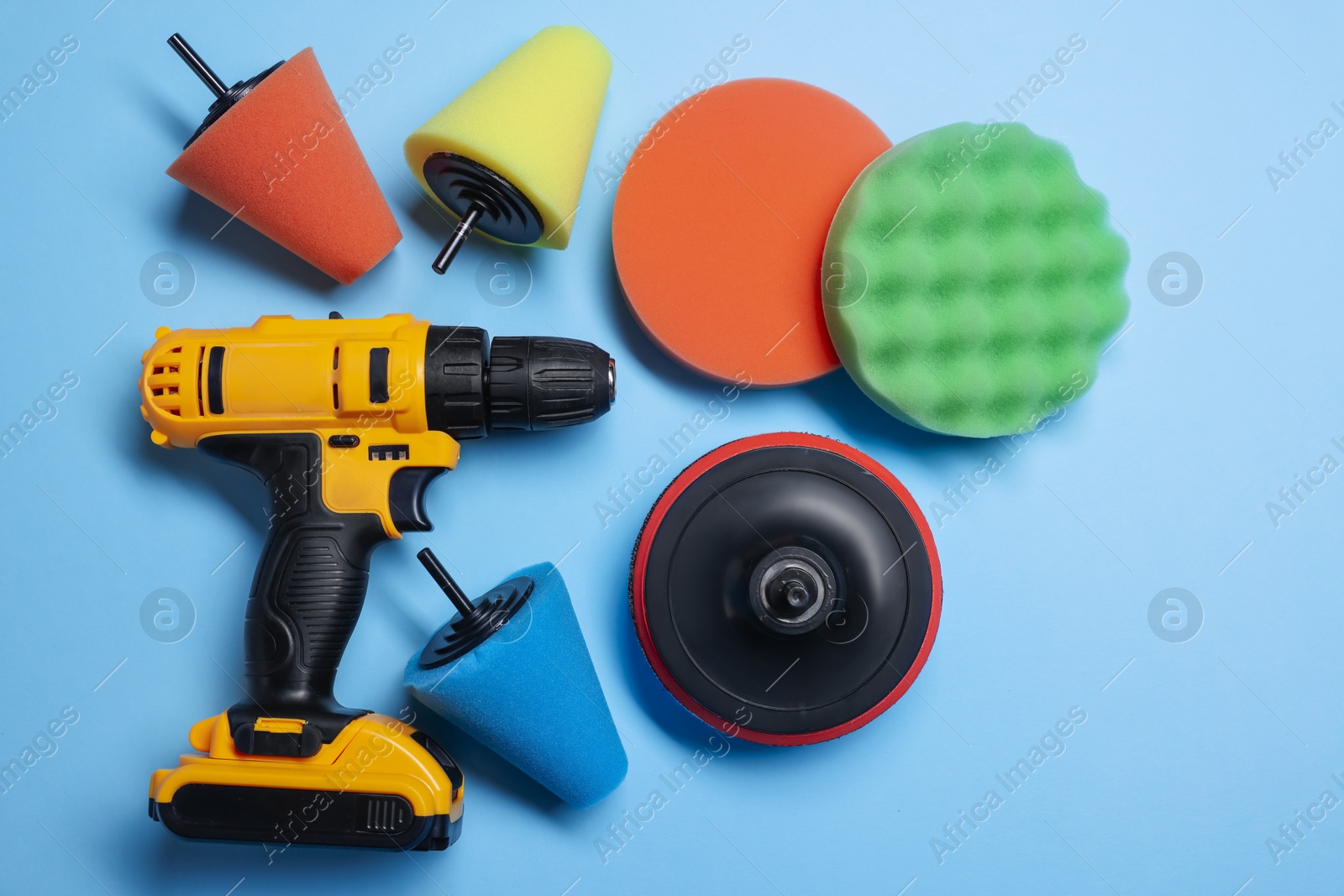 Photo of Electric screwdriver with different polish pads on light blue background, flat lay