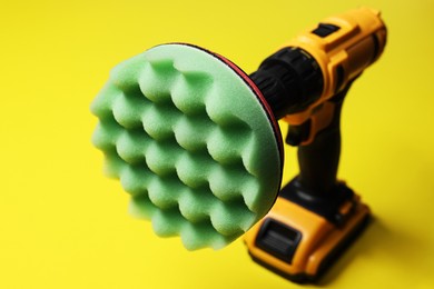 Photo of Electric screwdriver with polish pad on yellow background, closeup