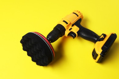 Photo of Electric screwdriver with polish pad on yellow background