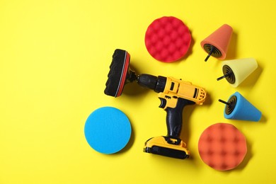 Photo of Electric screwdriver with different polish pads on yellow background, flat lay. Space for text