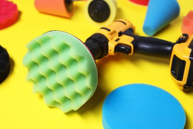 Photo of Electric screwdriver with different polish pads on yellow background, closeup