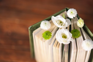 Photo of Book with beautiful flowers on table, closeup. Space for text