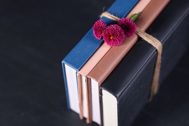 Photo of Books with beautiful flowers on dark table, closeup. Space for text