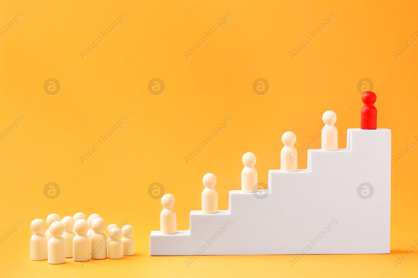 Photo of Human figures, red one on top of stairs against orange background. Competition concept