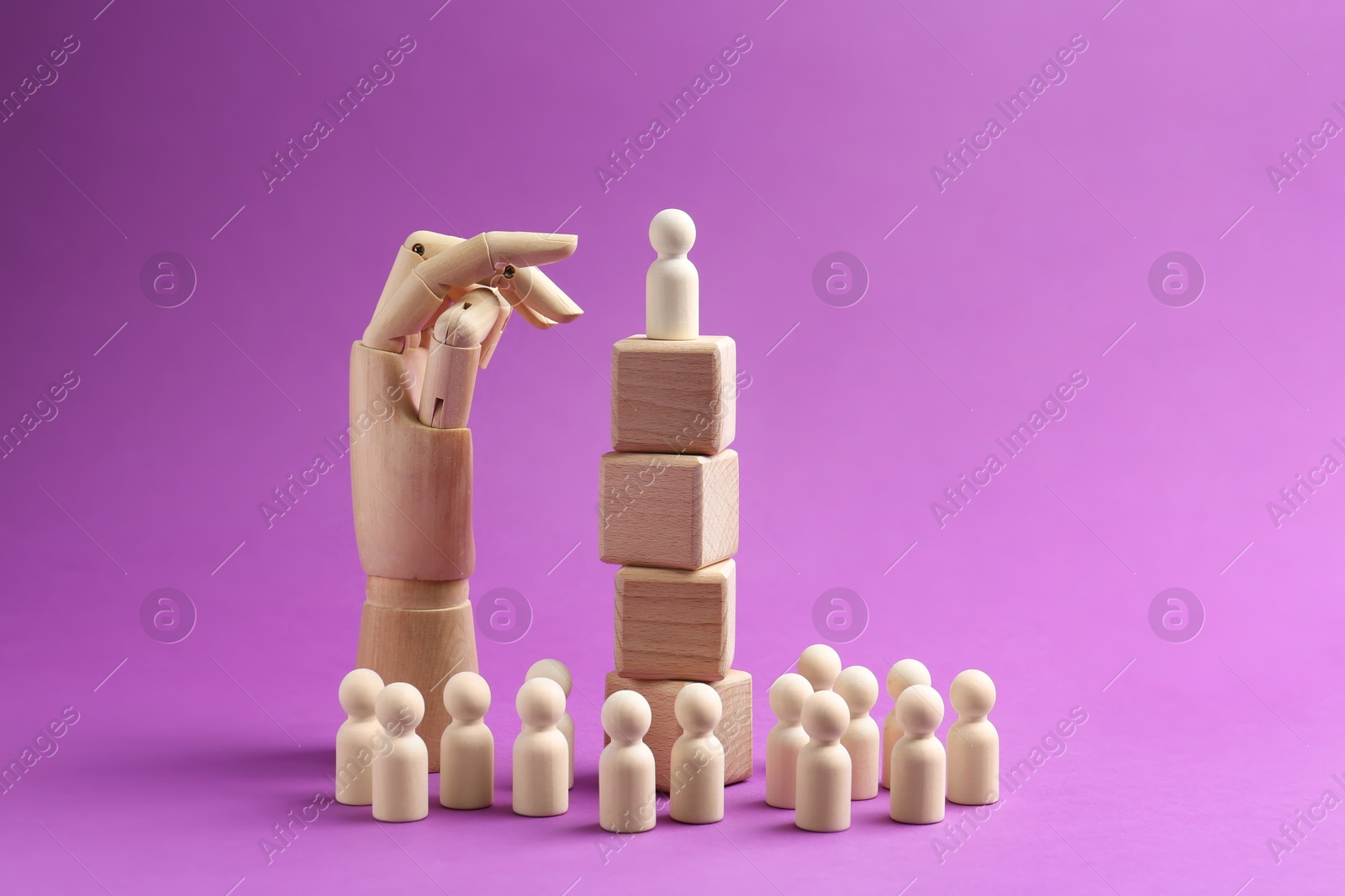 Photo of Human figures, wooden one on top of stacked cubes and mannequin hand against violet background. Competition concept