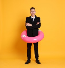 Photo of Businessman with inflatable ring on orange background