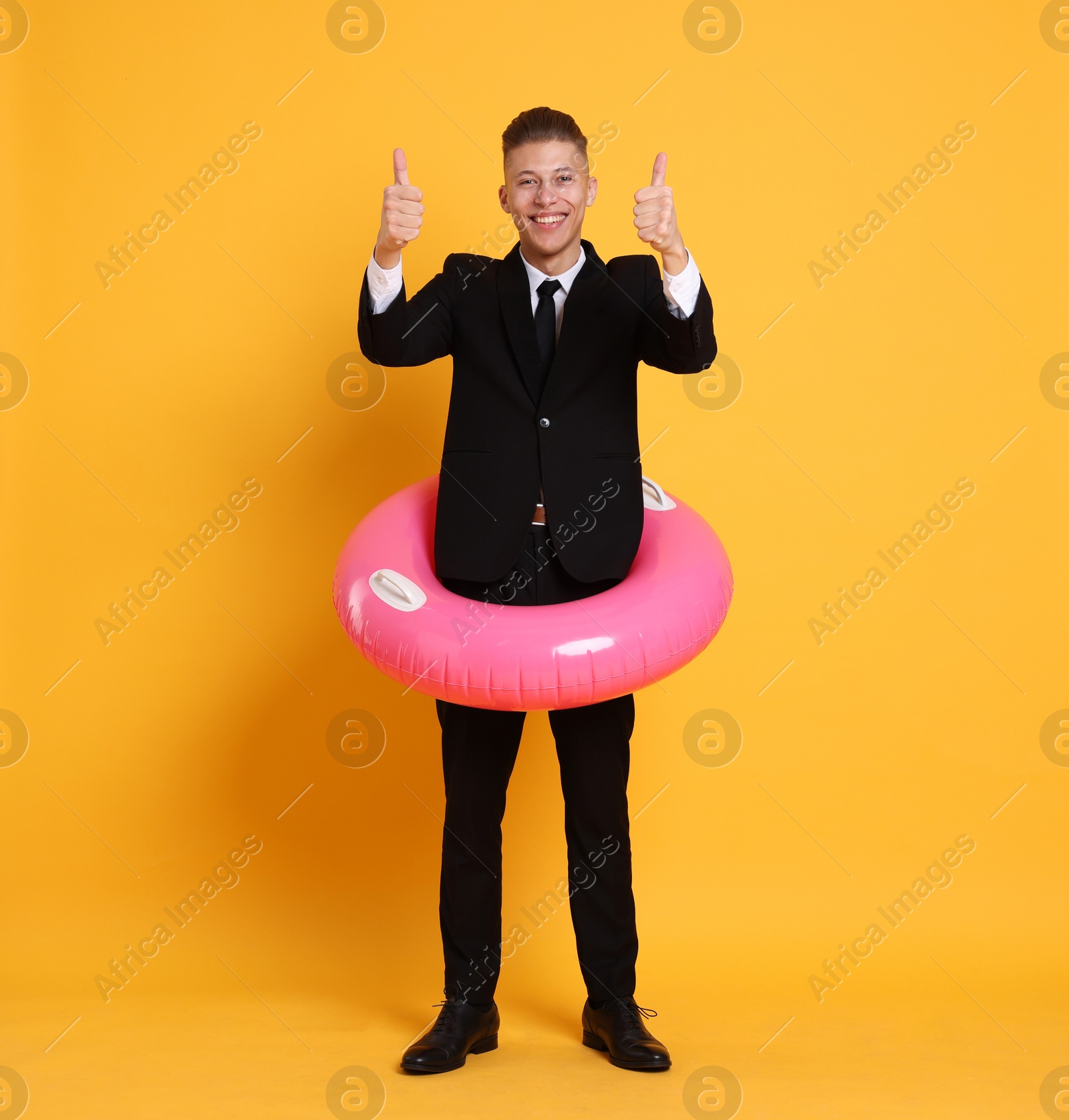 Photo of Businessman with inflatable ring showing thumbs up on orange background