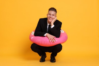 Photo of Businessman with inflatable ring on orange background