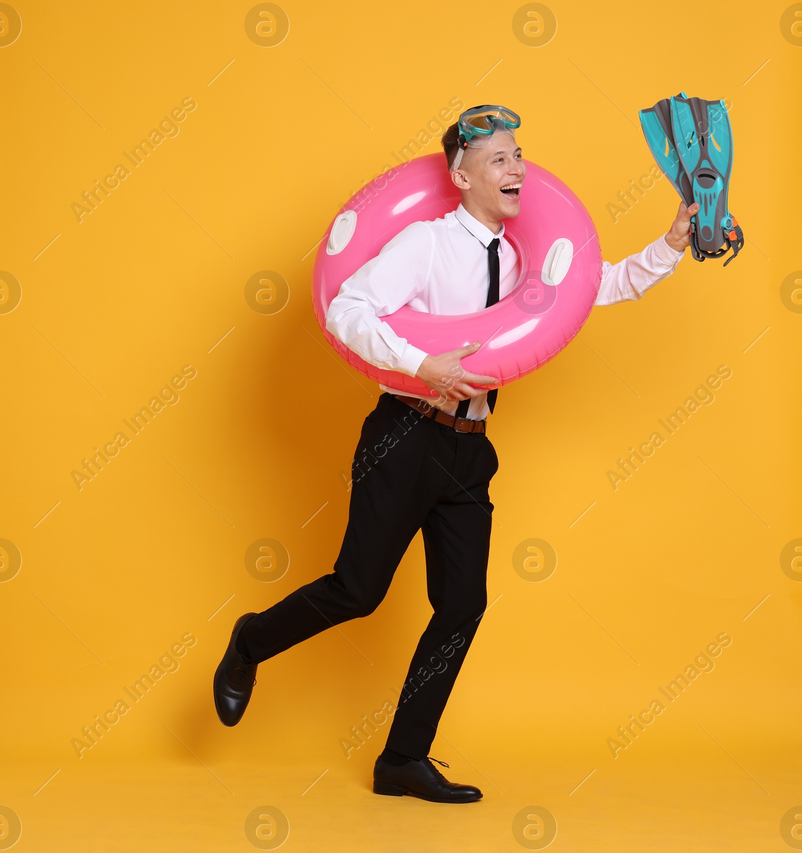 Photo of Businessman with inflatable ring, flippers and diving mask on orange background