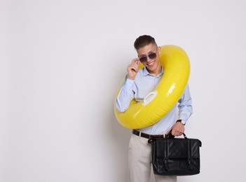 Photo of Businessman with inflatable ring and briefcase on white background, space for text