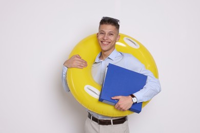 Photo of Businessman with inflatable ring and folder on white background