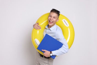 Photo of Businessman with inflatable ring and folder on white background