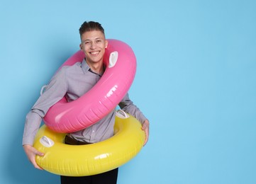 Photo of Businessman with inflatable rings on light blue background, space for text