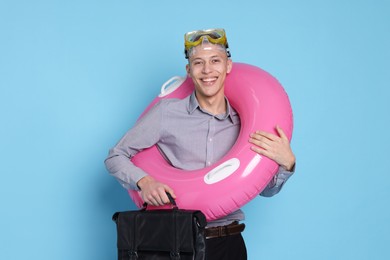 Photo of Businessman with inflatable ring, briefcase and diving mask on light blue background