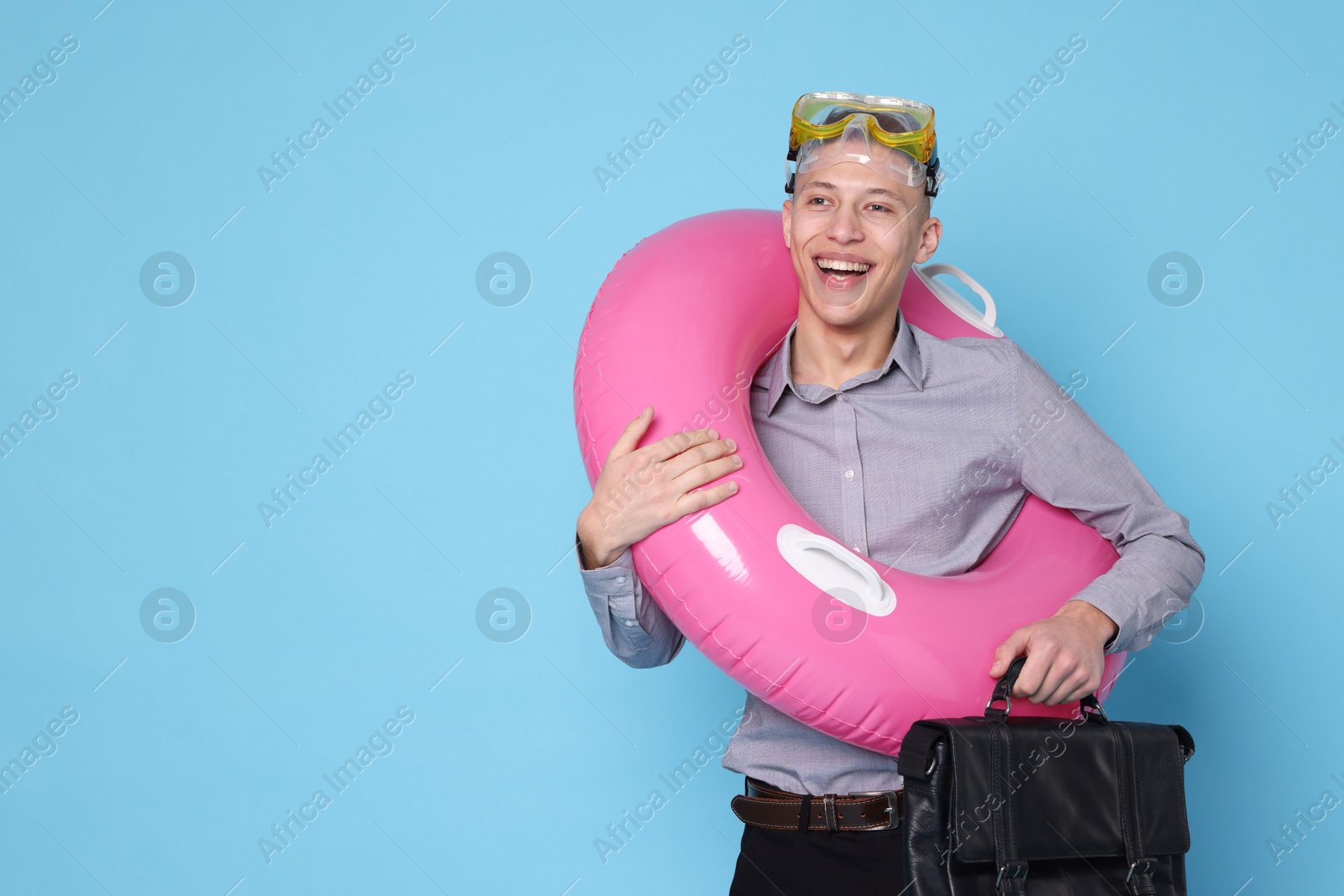 Photo of Businessman with inflatable ring, briefcase and diving mask on light blue background, space for text