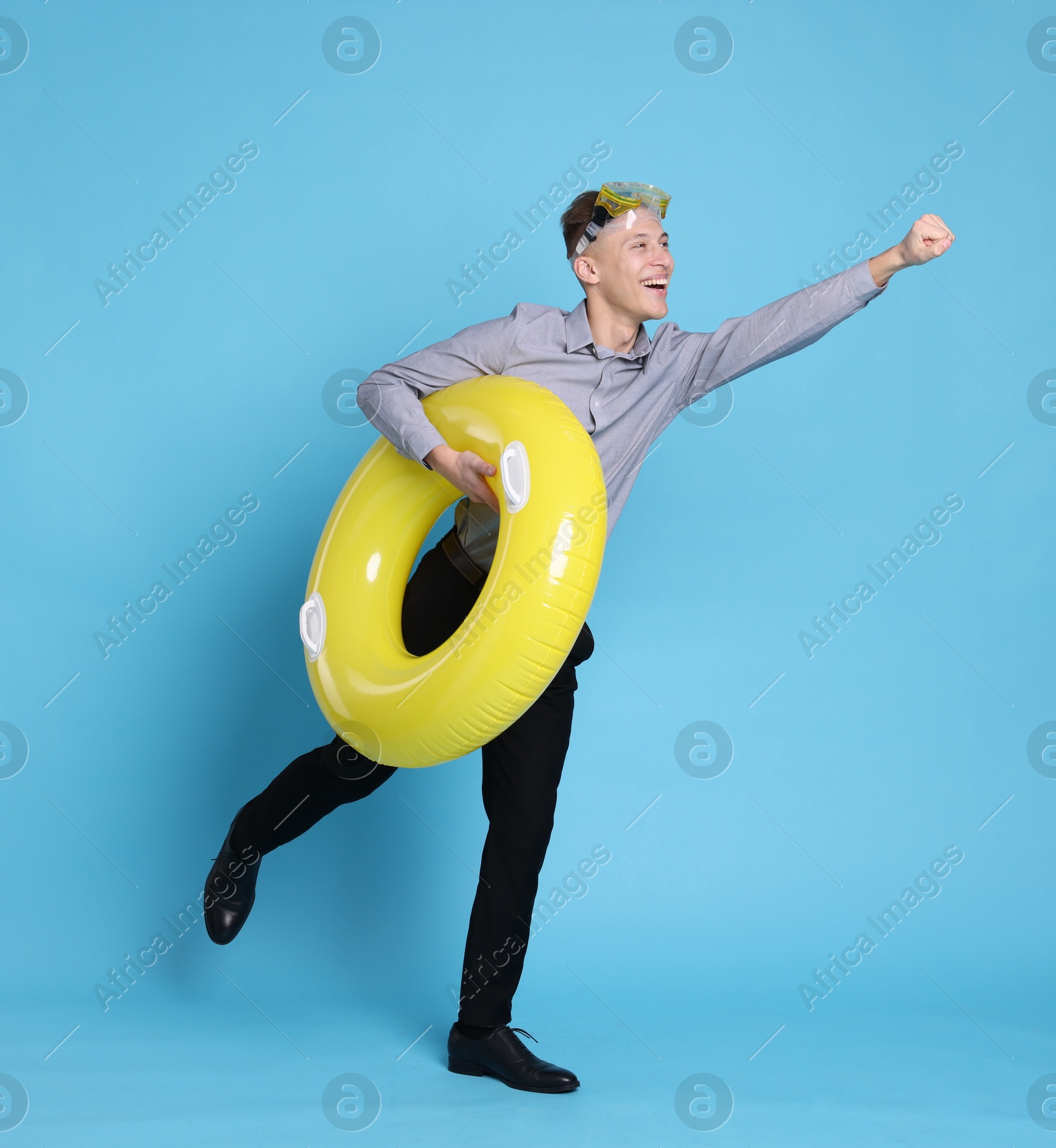 Photo of Businessman with inflatable ring and diving mask on light blue background