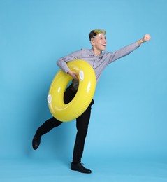 Photo of Businessman with inflatable ring and diving mask on light blue background