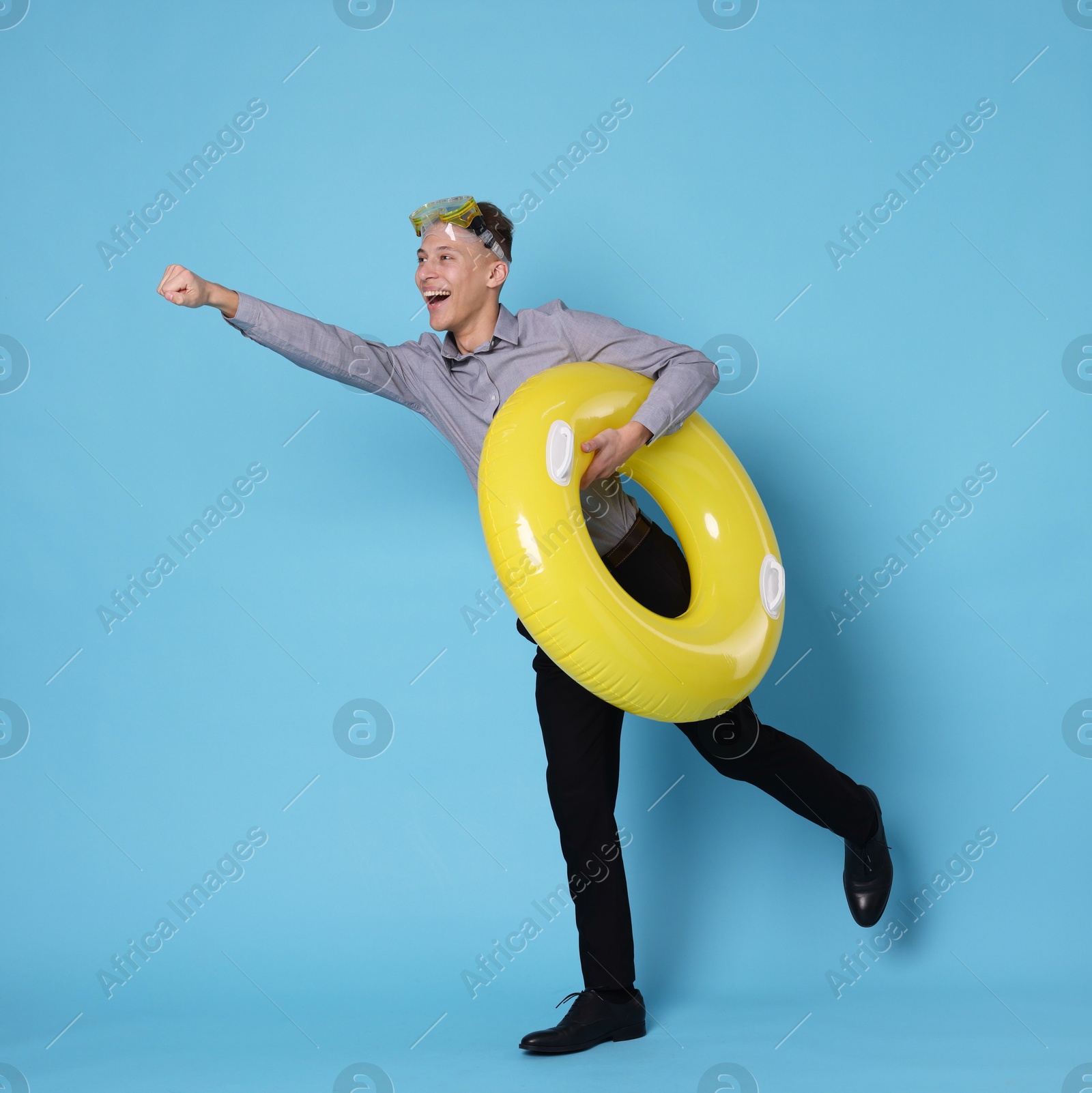 Photo of Businessman with inflatable ring and diving mask on light blue background